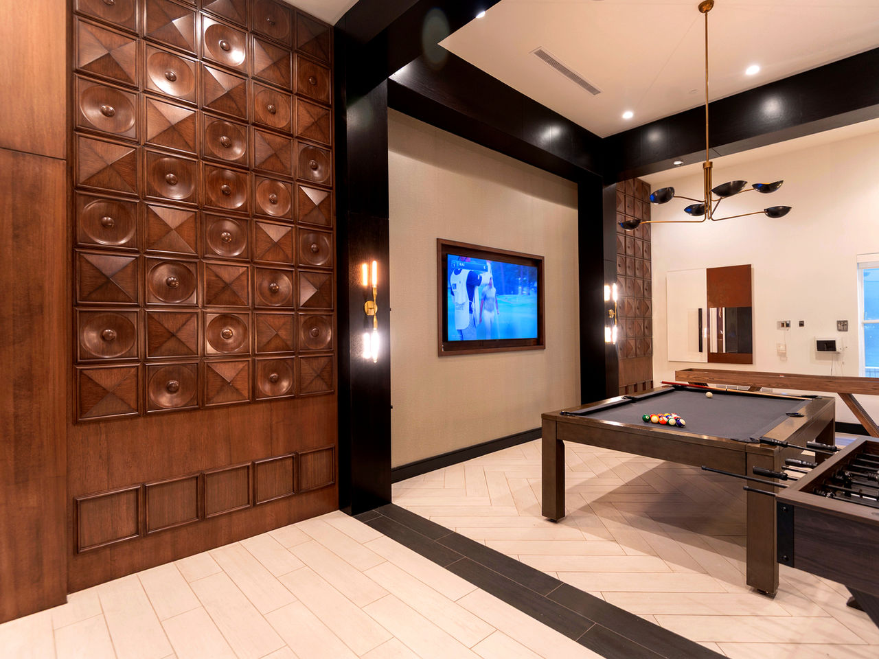 Multifamily game room with a custom carved wood feature wall